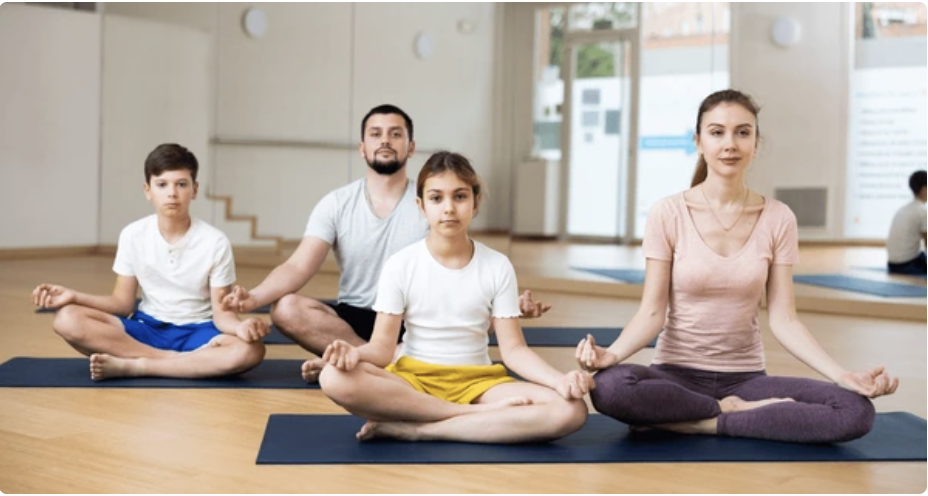 family of four meditating together at home for mental peace and mindfulness